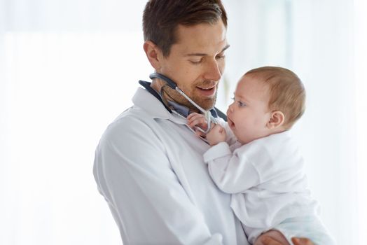 Filled with curiosity. Portrait of a handsome male doctor holding an adorable baby.