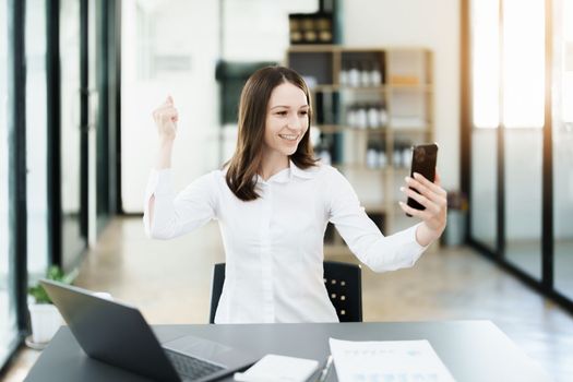 Excited businesswoman using mobile phone while in office.