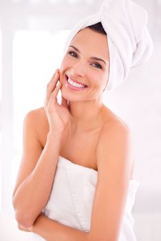 Complete body pampering. A beautiful woman touching her skin while standing wrapped in her towel.