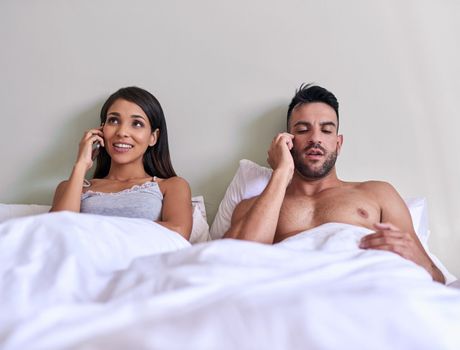 This is our wake up calls. a young married couple on a call in their bed at home.