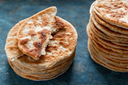 Flatbread lavash, chapati, naan, heap of tortilla on a blue background Homemade flatbread stacked.