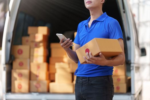 Asian courier with parcel and delivery logistic concept. Delivery man using delivery app by smartphone