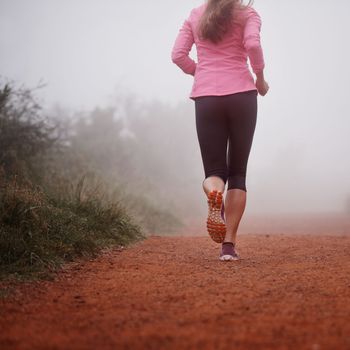 Nothing like a misty morning run. a woman running on a trail on a misty morning.