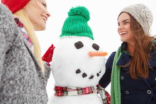 Women, snow and snowman with Christmas selfie and holiday, winter break in Canada with festive spirit and tradition with friends outdoor. Nature, smile in picture and happy with Xmas and celebration.