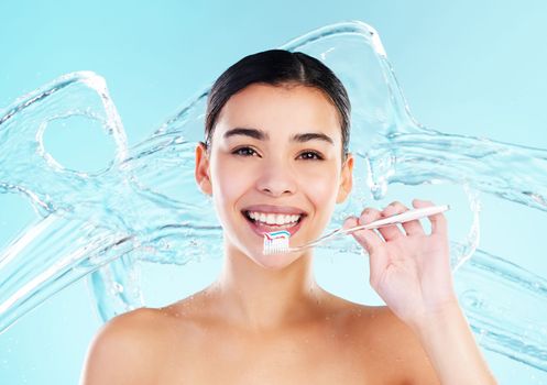 Oral health is wealth. a young woman brushing her teeth against a studio background.