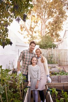 This family is going green. Portrait of a happy family gardening together in their backyard.