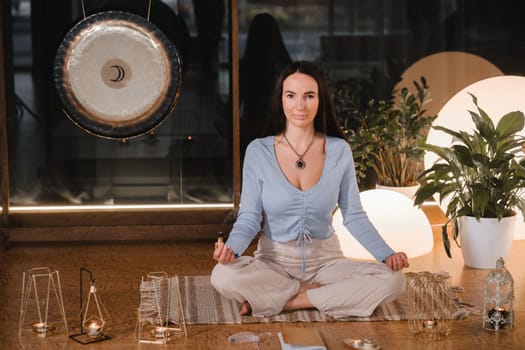 A woman is sitting in a lotus position with scented candles in her hands in the gym