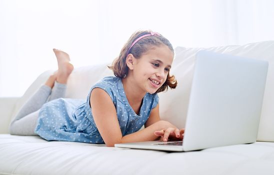 Exploring the world wide web. a young girl using a laptop at home.
