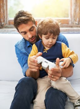 Now youre getting the hang of it. a father and his young son playing video games.