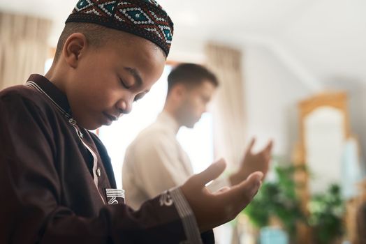 Irrational fears only submit to prayer. a young muslim man and his son praying in the lounge at home.