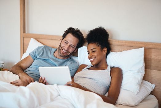 Heres a few options to choose from. a couple using a digital tablet while lying in bed together.