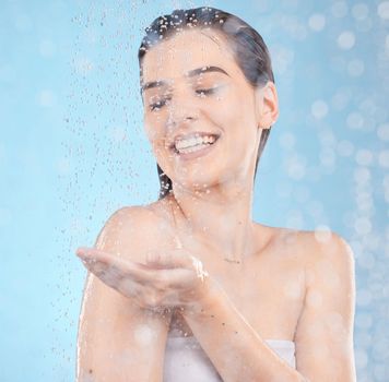 Beauty splash, skincare and woman in a shower for luxury, wellness and cleaning in studio with mockup. Water splash, model and girl relax in water, face and hair, care and moisture on blue background