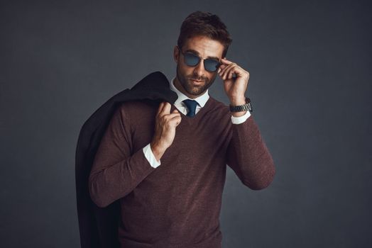 Killing the style game. Studio portrait of a stylishly dressed young man carrying his jacket against a gray background.
