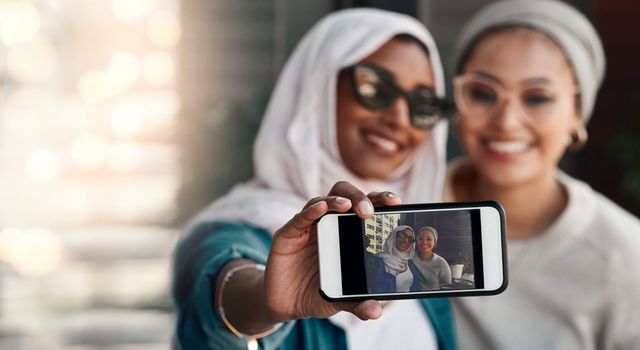 Photogenic is what they are. Cropped shot two affectionate young girlfriends taking a selfie together at a cafe while dressed in hijab.