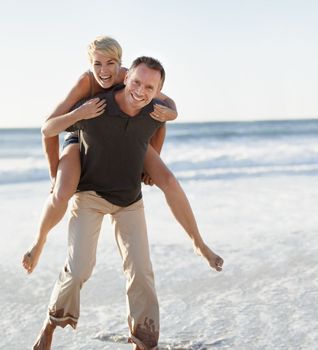 They seize every day. A husband giving his wife a piggyback ride on the beach.