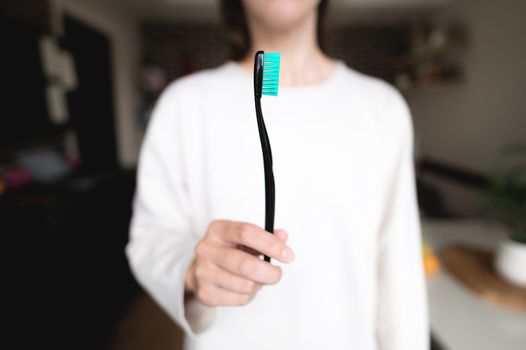 Woman holding a toothbrush in the foreground in focus, blurred background. Oral hygiene