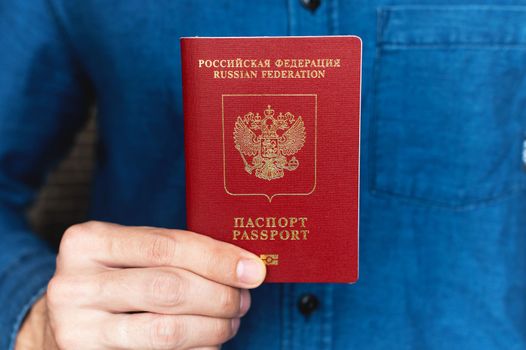 close-up of a man's hand in a shirt holding a foreign passport, the concept of preparing for a vacation