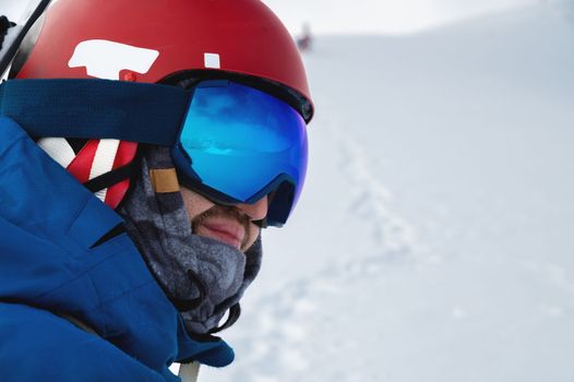 male athlete in a snowboard helmet and ski goggles looks into the distance, profile portrait