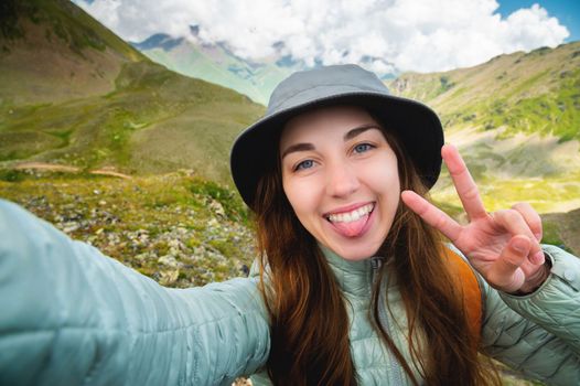 Young woman taking selfie portrait hiking mountains - Happy hiker on the top of the cliff smiling at camera - Travel and hobby concept.