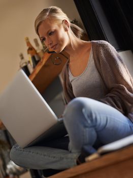 Food blogging is a hobby and passion. An attractive young woman using her laptop while relaxing at home on her kitchen counter