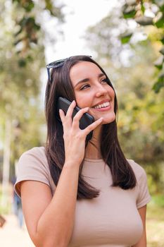 smiling young woman calling by phone in a park