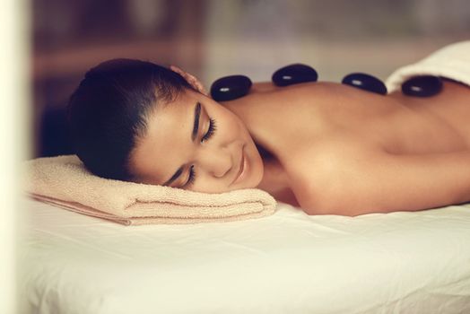 Enjoying the soothing sensation of the hot stones. A young woman receiving a hot stone treatment at a spa.