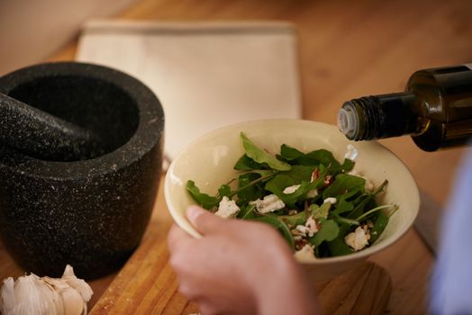 Healthy eating. a woman pouring oil over a bowl of salad.
