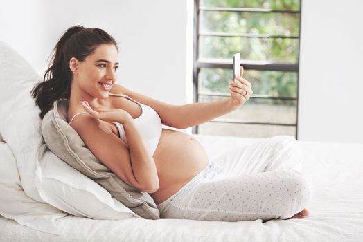 These are the moments worth remembering. a pregnant woman taking a selfie at home.