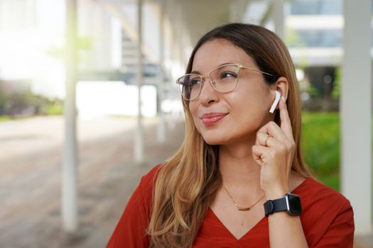 Close-up of business woman press with finger on her wireless earphone outdoor