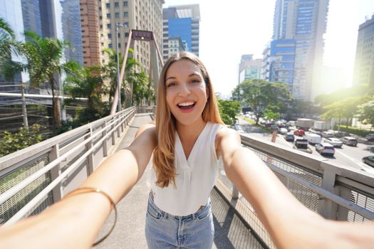 Tourism in Sao Paulo. Beautiful smiling girl takes self portrait in Moema financial district of Sao Paulo, Brazil.