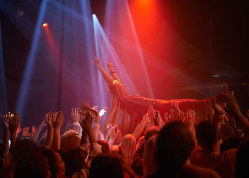 Surfing on a crowd of fans. A stage diver being carried across the audience at a rock concert.