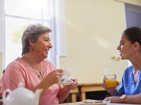 Tea is always served with a side of chit chat. a caregiver chatting to a senior patient in a nursing home.