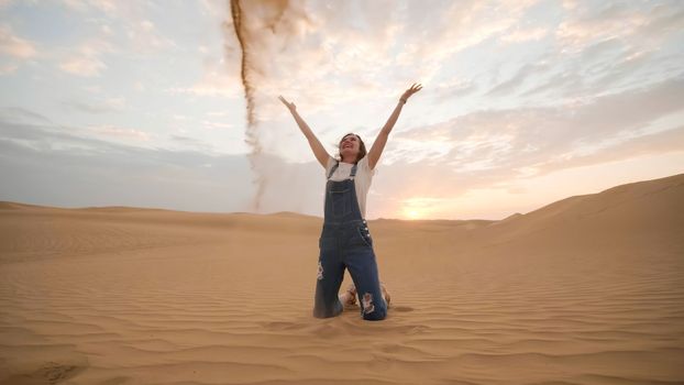 A happy girl in the desert of the Arab Emirates throws up sand.