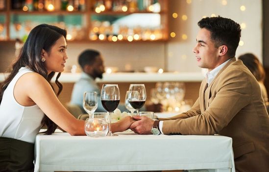 Couple holding hands, date in restaurant and celebrate Valentines day holiday with love, romance and fine dining. Commitment, interracial relationship and man with woman together, trust and support.