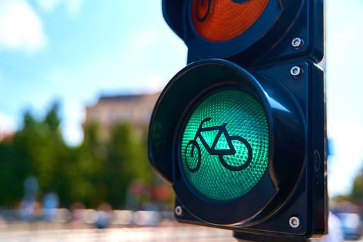 Close-up of a traffic light for cyclists, which is glowing green. A bicycle is shown on the traffic light