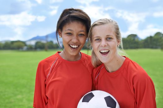 Young soccer stars. Portrait of two young female soccer players standing on a soccer field.