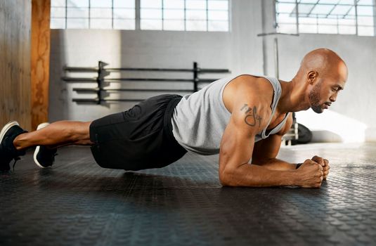 Hold the pose for as long as you can. a young man completing a plank session.
