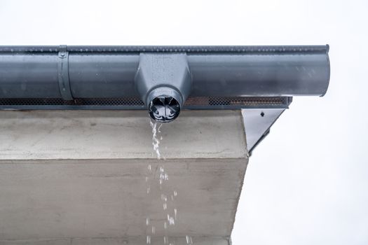 gutter with flowing rainwater on the roof of the building