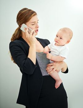 Shes got work and motherhood covered. a successful young businesswoman carrying her adorable baby boy while talking on the phone.