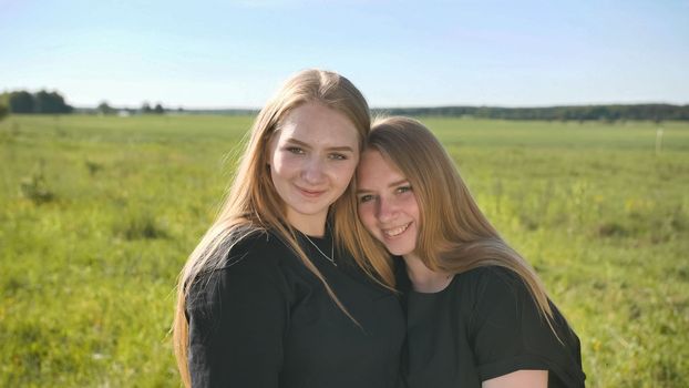 Portrait of two twin sisters in the field on a warm summer day