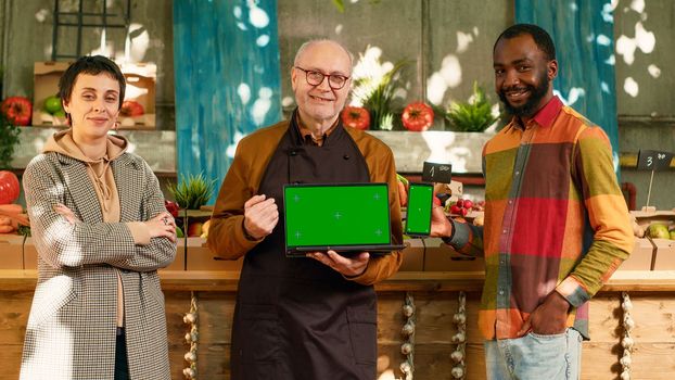 Diverse group of people showing greenscreen on laptop and smartphone