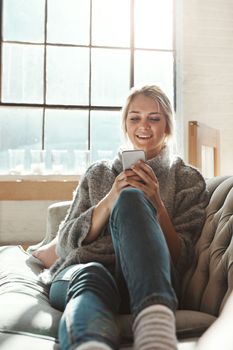 Woman, sofa and phone with smile, chat and communication on internet to relax in lounge. Girl, couch and texting on social network, mobile tech or streaming video for comedy, meme and happy in house