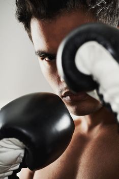 Hes dedicated to the sport of boxing. Closeup portrait of a young male boxer in a fighting stance.