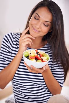 Healthy eating equals a great life. a young woman looking thoughtfully at her fruit salad.