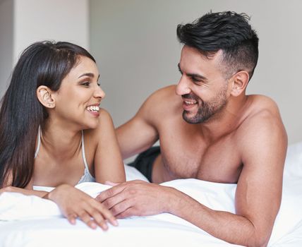 Start the day with laughter. an affectionate young married couple in bed at home.