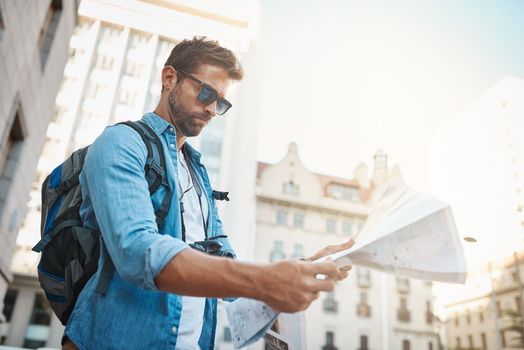 Travel is an investment in yourself. a young man looking at a map while touring a foreign city.