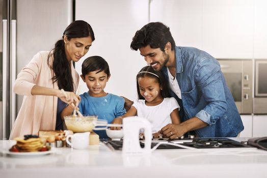 Breakfast always tastes better when you make it yourself. an affectionate young family cooking breakfast in their kitchen at home.