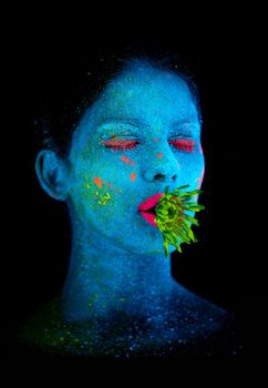 Enter the realm of the fantastical. a young woman posing with neon paint on her face.