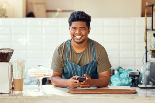 Barista portrait, cafe black man on a phone for happy online sales, small business management or ecommerce. Smile waiter, cashier or worker person on smartphone, technology or service in restaurant