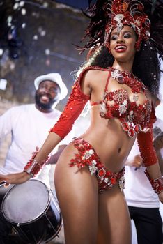 Turning beats into heat. a beautiful samba dancer performing in a carnival with her band.